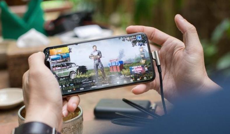 Ilustrasi bermain handphone sambil mengisi daya baterai. (Foto: Istimewa)