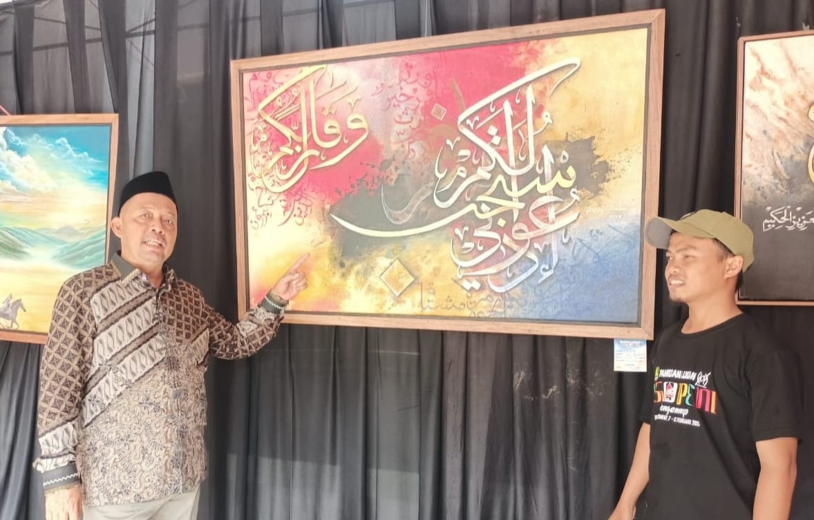 Ketua DPRD Sumenep, H. Zainal Arifin saat menunjukkan lukisan kaligrafi karya Haris Muhammad. (Foto: Hayat/warta9.co.id)