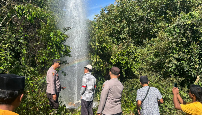 Aparat kepolisian bersama warga mendatangi lokasi semburan air dari sumur bor yang mengeluarkan aroma gas. (Foto: Hayat/Warta9)
