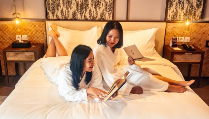 Dua tamu menikmati suasana nyaman di salah satu kamar MYZE Hotel Sumenep by ARTOTEL. Hotel ini menghadirkan promo spesial bagi pemilik KTP Madura berupa potongan harga menginap dan diskon bersantap di Sae Rassa Restaurant. (Dok. MYZE Hotel Sumenep)